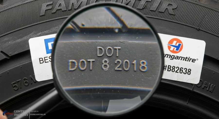 نمای نزدیک از دیواره لاستیک که کد تاریخ تولید (DOT) به وضوح با ذره‌بین مشخص شده است، به همراه لوگوی hamgamtire به رنگ #B82638 به عنوان نمادی از خرید لاستیک اصل و با تاریخ جدید.